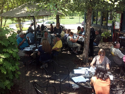 workshop attendees sitting at tables in a shaded area