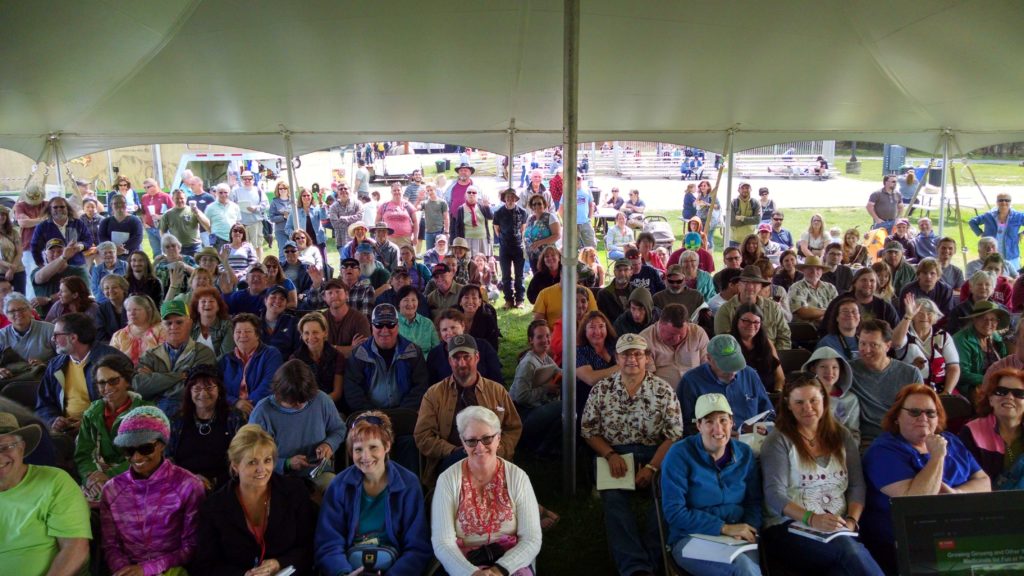 An audience of smiling people in a tent