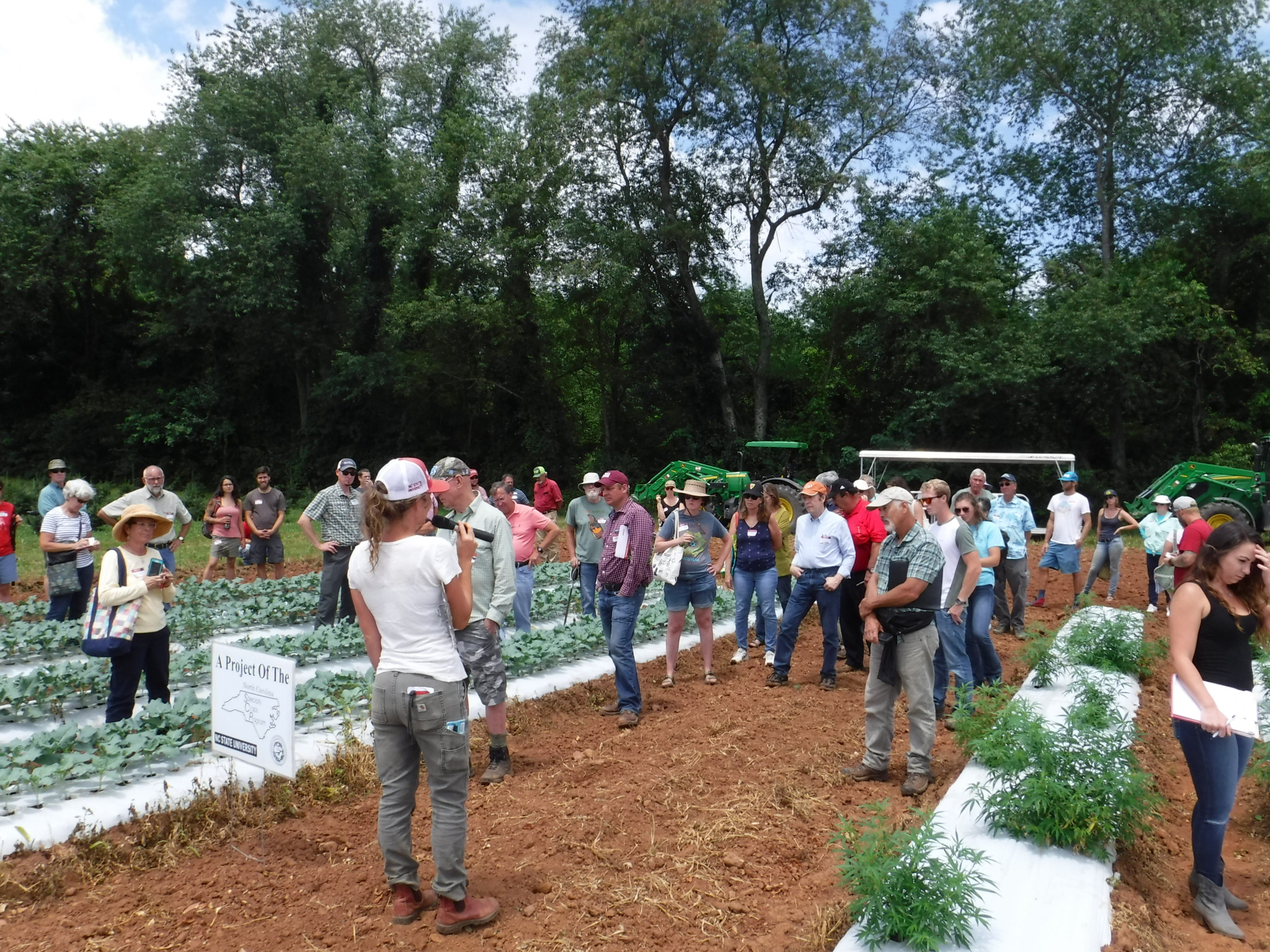 researcher talking to people in a field plot